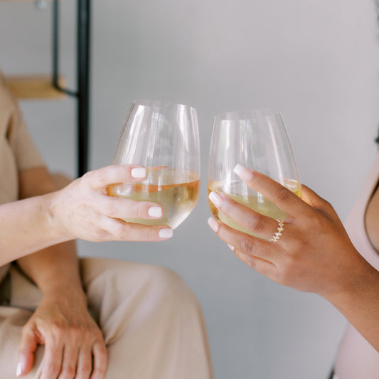 two women's hands toasting wine glasses